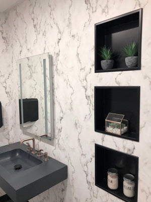 Three stacked Ally wall niches, 12 × 12 in, matte black, in a white marble wall beside a sink