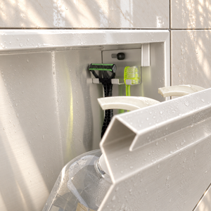 Close-up of the inside of the door niche, 12 × 12 in door, matte white: hooks holding a razor, a toothbrush and a bottle