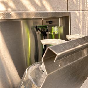 Close-up of the inside of the door niche, 12 × 12 in door, brushed stainless steel: hooks holding a razor, a toothbrush and a bottle