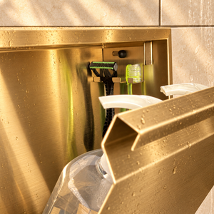 Close-up of the inside of the door niche, 12 × 12 in door, gold PVD: hooks holding a razor, a toothbrush and a bottle