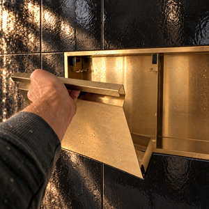 A hand lifts the removable door off the door niche, 12 × 48 in, gold PVD