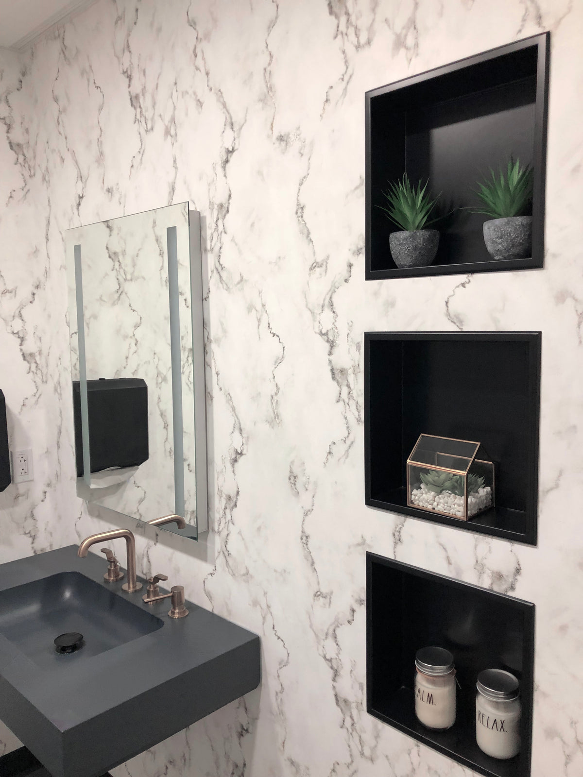 Trois niches Ally 12 × 12 po en noir mat superposées dans un mur de marbre blanc véiné, avec plante et objets décoratifs