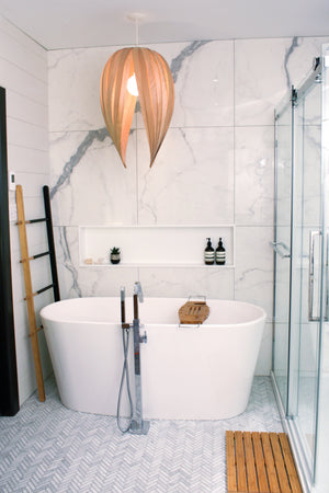 Niche Alba 12 × 48 po en blanc mat dans un mur de marbre, au fond d’une salle de bain avec baignoire autoportante et douche vitrée