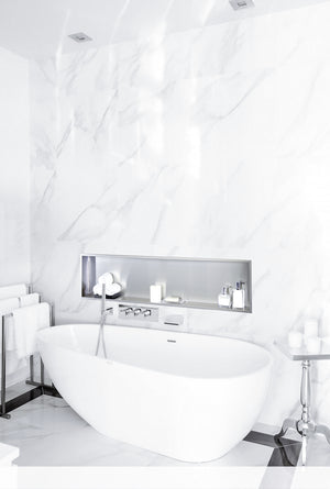 Niche Alba 12 × 48 po en acier inoxydable brossé encastrée dans un mur de marbre blanc au-dessus d’une baignoire autoportante