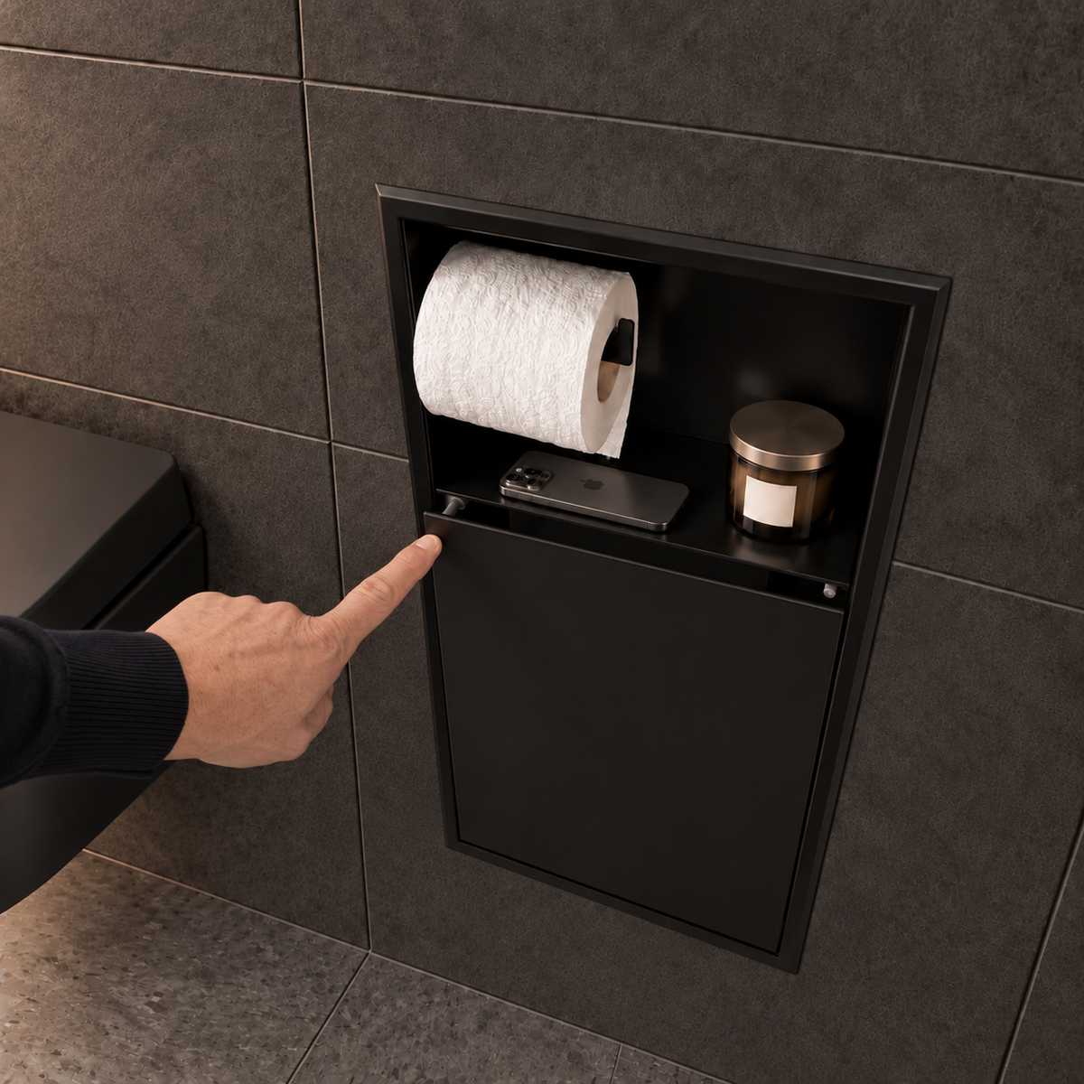 Une main appuie sur la porte de la niche WC noir mat 24 × 10,5 po : elle s'ouvre par simple pression