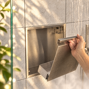 A hand lifts the removable door off the door niche, 12 × 12 in, brushed stainless steel
