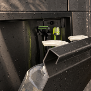 Close-up of the inside of the door niche, 12 × 12 in door, matte black: hooks holding a razor, a toothbrush and a bottle