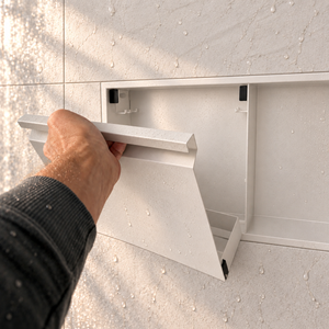 A hand lifts the removable door off the door niche, 12 × 24 in, matte white
