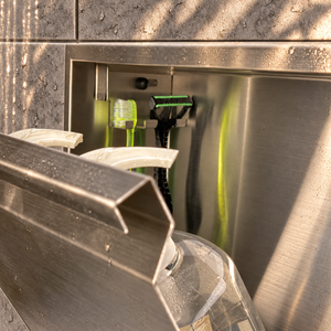 Close-up of the inside of the door niche, 12 × 24 in door, brushed stainless steel: hooks holding a razor, a toothbrush and a bottle