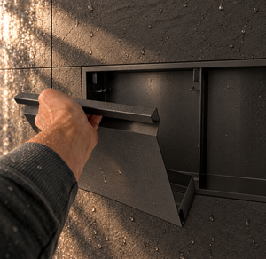 A hand lifts the removable door off the door niche, 12 × 24 in, matte black