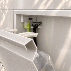 Close-up of the inside of the door niche, 12 × 48 in door, matte white: hooks holding a razor, a toothbrush and a bottle