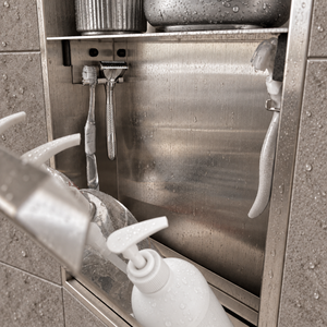 Close-up of the inside of the door niche, 24 × 12 in door, brushed stainless steel: hooks holding a razor, a toothbrush and a bottle