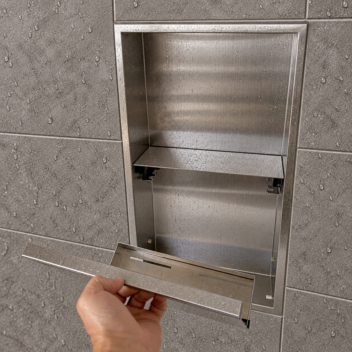 A hand lifts the removable door off the door niche, 24 × 12 in, brushed stainless steel