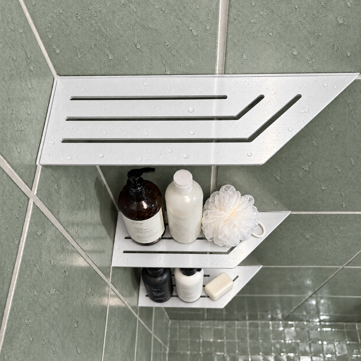 Corner shelf, 4 × 12 in, glossy white, bottles and a shower puff on the lower shelves, in a tiled shower