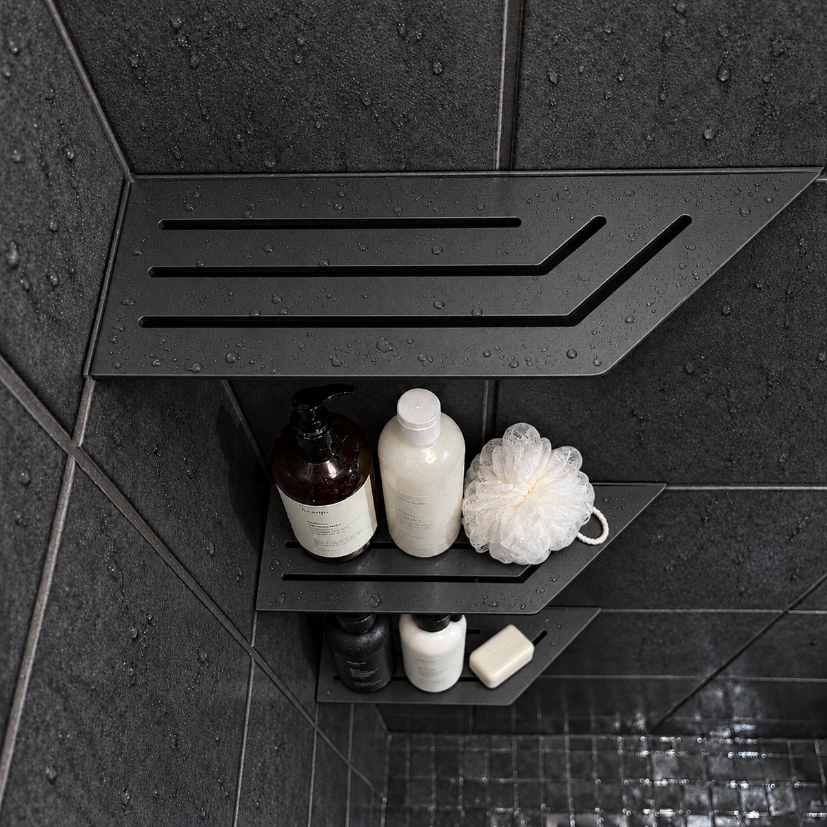Corner shelf, 4 × 12 in, matte black, bottles and a shower puff on the lower shelves, in a tiled shower